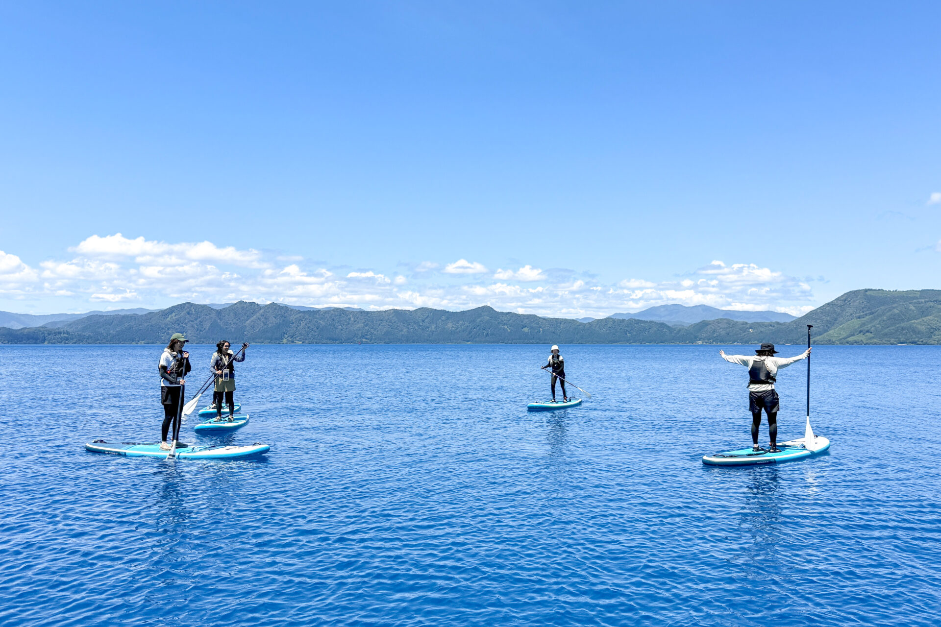 田沢湖ブルーの湖上でSUPツアーを楽しむ参加者たち