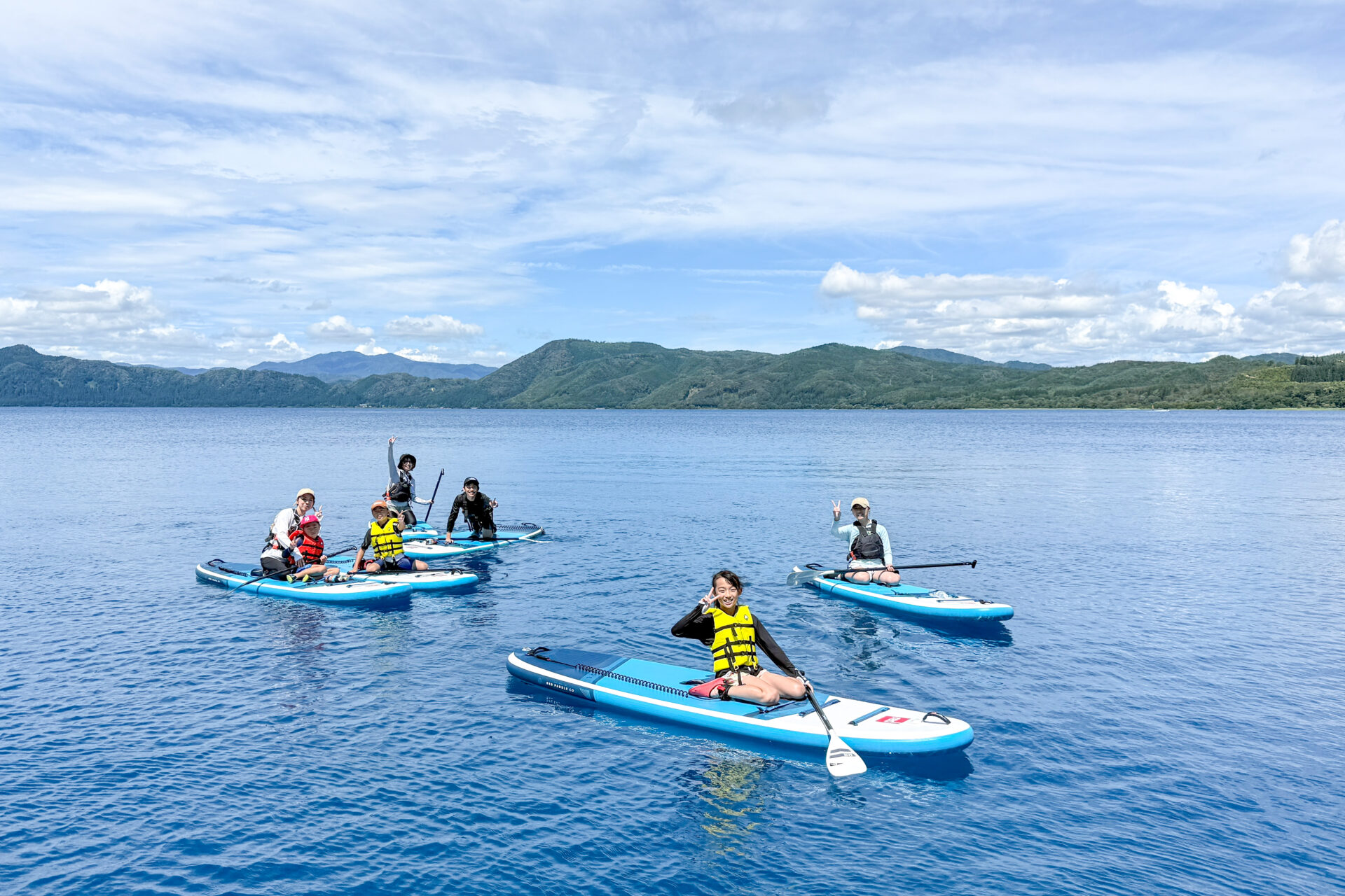 日中の田沢湖SUPツアーで、子供と一緒に湖上を楽しむ家族
